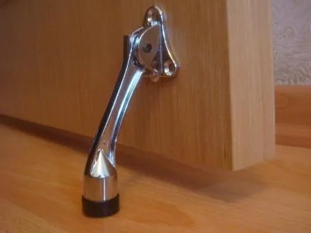 упор дверной «козья ножка», демонстрирующий устойчивость. изображение упора, демонстрирующее его устойчивость;